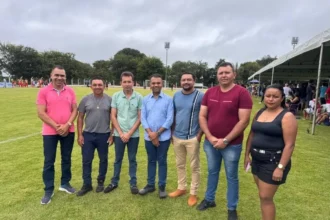 Deputado Moisemar Marinho e prefeito Nereu Fontes observam partida da 3ª Copa Society Ferrujão em Oliveira de Fátima, Tocantins, com jogadores em campo.
